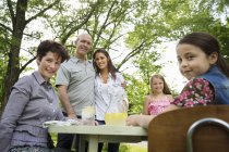 Famiglia che si riunisce al tavolo da giardino e fa limonata fresca . — Foto stock