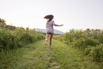 Rear view of woman running along path in green meadow. — Stock Photo