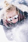Young woman in sunglasses blowing fresh snow off hands. — Stock Photo