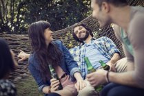 Cheerful friends relaxing with beer in hammock. — Stock Photo