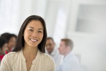 Femme d'affaires confiante debout dans la salle de réunion avec des collègues en arrière-plan . — Photo de stock