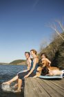 Family and retriever dog on jetty by lake. — Stock Photo