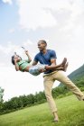 Man lifting son in arms while playing outdoors. — Stock Photo