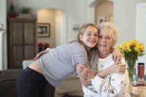 Adolescente ragazza abbracciando donna anziana in casa interiore . — Foto stock