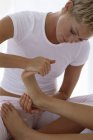 Woman holding female foot and massaging and toes. — Stock Photo