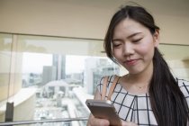 Junge Japanerin benutzt Smartphone in Bürogebäude. — Stockfoto