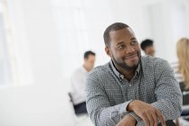 Mid adult man sitting separately from group of people at business meeting in office. — Stock Photo