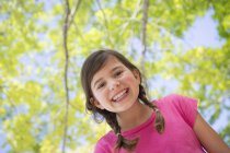 Elementary age girl with braids under canopy of trees, portrait. — Stock Photo