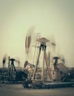 Funktionierende Ölindustrie pumpt in der Mitte des Sonnenuntergangs Ölfeld in Kalifornien, Vereinigte Staaten — Stockfoto