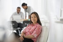 Femme asiatique se détendre sur le canapé de bureau avec des collègues en utilisant un ordinateur portable en arrière-plan . — Photo de stock