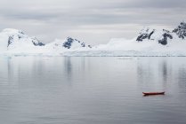 Small kayak boat on calm water off Antarctic island shore. — Stock Photo