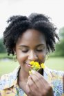 Retrato de mujer joven oliendo flores amarillas . - foto de stock