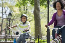 Мать и сын катаются на велосипеде по дорожке в солнечном парке . — стоковое фото