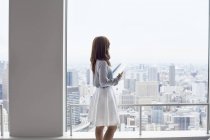 Femme tenant des dossiers et regardant la vue dans un immeuble de bureaux . — Photo de stock