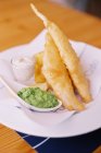 Fried battered fish and chips with mushy peas and tartar sauce on plate. — Stock Photo