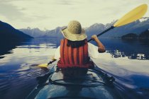 Rear view of woman kayaking on calm water of Muir Inlet in Glacier Bay National Park, USA. — Stock Photo