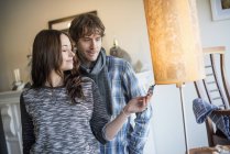 Smiling couple standing in shop and checking floor lamp price tag. — Stock Photo