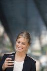 Junge Geschäftsfrau in schwarzer Jacke mit Smartphone in der Stadt. — Stockfoto
