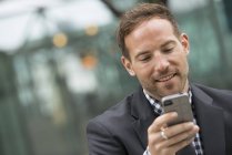Mann mit kurzen roten Haaren und Bart im Anzug mit Smartphone in der Stadt. — Stockfoto