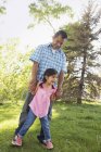 Padre de la mano con la hija de edad elemental en el parque . - foto de stock