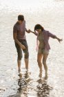 Casal de mãos dadas enquanto remando em águas rasas no lago . — Fotografia de Stock