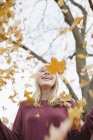Lachende Teenager werfen Herbstblätter in Park in die Luft. — Stockfoto