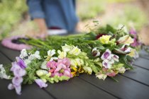 Mazzo di fiori estivi sul tavolo da giardino con persona sullo sfondo . — Foto stock
