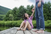 Пара тримає руки на дерев'яному джуті біля сільського озера . — стокове фото