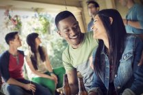 Man and woman drinking beer with fiends at house party. — Stock Photo