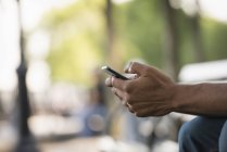 Close-up of male hands using smartphone in city park. — Stock Photo