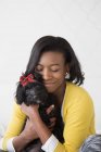 Teenage girl cuddling small black pet dog with red bow. — Stock Photo