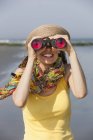 Woman in sunhat and scarf using binoculars on beach on New Jersey Shore, USA. — Stock Photo