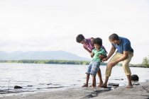 Family with son playing on shore of lake in woodland. — Stock Photo