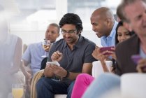 Pequeño grupo de personas revisando teléfonos inteligentes en reuniones sociales en interiores . - foto de stock