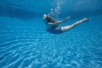 Chica preadolescente con abanico de pelo largo nadando bajo el agua en la piscina
. - foto de stock