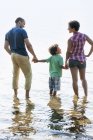 Família com filho em pé na água na margem do lago . — Fotografia de Stock
