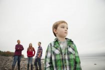 Adolescentes e menino de idade elementar em pé na costa . — Fotografia de Stock