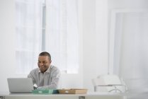 Cheerful mid adult man using laptop at modern office desk. — Stock Photo