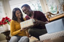 Tiefansicht des Paares durch Sofa beim Austausch von verpackten Geschenken. — Stockfoto