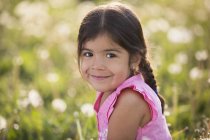 Menina idade elementar com cabelos castanhos e tranças no prado de flores selvagens . — Fotografia de Stock