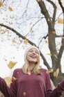Весела дівчинка-підліток кидає акушерське листя в повітря в парку . — стокове фото