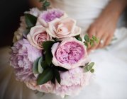 Nahaufnahme der Braut mit Brautstrauß aus rosa Rosen und Pfingstrosen. — Stockfoto