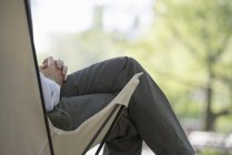 Abgeschnittene Ansicht eines Mannes, der im Campingstuhl im Park sitzt. — Stockfoto