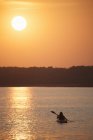 Mulher kayaker ao pôr do sol no lago calmo . — Fotografia de Stock