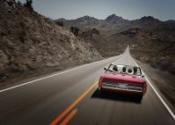 Red convertible car with young people on road trip. — Stock Photo