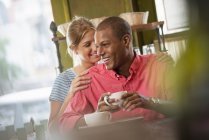 Жінка спирається на плече чоловіка, що має каву в інтер'єрі кафе . — стокове фото