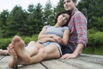 Junges Paar entspannt auf Holzsteg mit Blick auf Bergsee. — Stockfoto