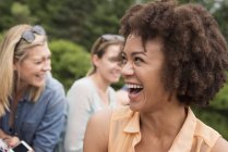 Jeune femme avec afro souriant en groupe d'amis à l'extérieur . — Photo de stock