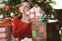 Adolescente chica temblando regalo por árbol de Navidad - foto de stock