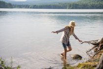Teenie-Mädchen mit Strohhut balanciert im flachen Wasser des Landsees. — Stockfoto